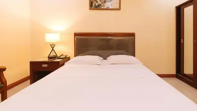 a bedroom with a large white bed and a lamp at Peace Hotel by RedDoorz in Manila