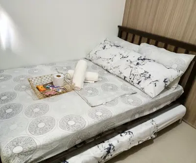 a bed with white and blue sheets and pillows at Adel's Cosy Place - SMDC Shore 2 Philippines in Manila