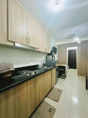 a kitchen with wooden cabinets and a counter top at Adel's Cosy Place - SMDC Shore 2 Philippines in Manila