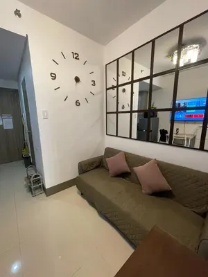 a living room with a couch and a clock on the wall at Condominium Fame Residence in Manila