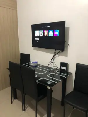 a dining room table with chairs and a flat screen tv at Shell Residence MOA Manila by JO Alano in Manila
