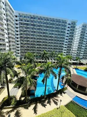 an aerial view of a resort with a pool and palm trees at Shell Residence MOA Manila by JO Alano in Manila