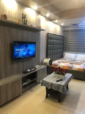 a living room with a television and a bed at Shell Residence MOA Manila by JO Alano in Manila