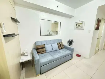 a living room with a blue couch and a mirror at Sea Residences by EXIN in Manila