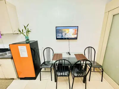 a table with chairs and a tv on a wall at Sea Residences by EXIN in Manila