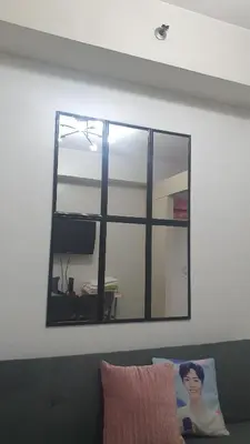 a mirror hanging on a wall above a couch at Sea Residences EZBedz in Manila