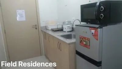 a small kitchen with a refrigerator and a microwave at Field Residences in Manila