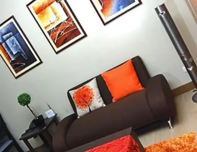 a living room with a couch and pictures on the wall at High-Rise Apartment Condo near NAIA Terminal 3 with a Perfect Airport Front-View in Manila