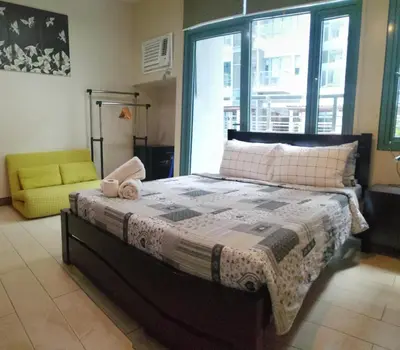 a bedroom with a bed and a chair and a window at Palm Tree Two Villas in Manila