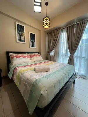 a bedroom with a large bed and a large window at Palm Tree Two Villas in Manila