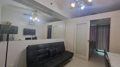 a living room with a black leather couch and a mirror at EZPlace Sea Residences in Manila