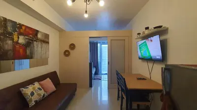 a living room with a couch and a table and a tv at EZPlace Sea Residences in Manila
