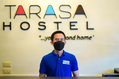 a man wearing a mask in front of a sign at TARASA HOSTEL in Manila