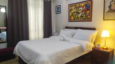 a bedroom with a large bed with white sheets at Affordable Suite at 150 Newport Blvd near NAIA T3 in Manila