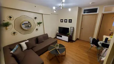 a living room with a couch and a television at The Lancris Residences, 2 Bedrooms, 1 Bathroom, Living-room, Kitchen & Pool is Free in Manila