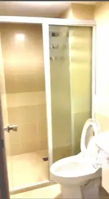 a bathroom with a toilet and a glass shower at The Lancris Residences, 2 Bedrooms, 1 Bathroom, Living-room, Kitchen & Pool is Free in Manila