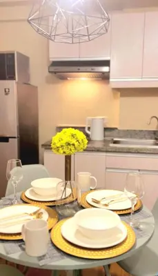 a dining room table with white plates and yellow flowers at The Lancris Residences, 2 Bedrooms, 1 Bathroom, Living-room, Kitchen & Pool is Free in Manila