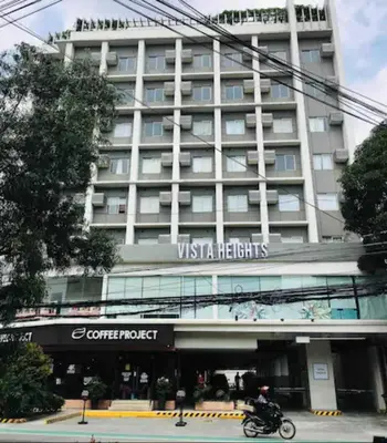 a man riding a motorcycle in front of a hotel at R'Holistay Vista Heights Legarda near CEU San Beda in Manila