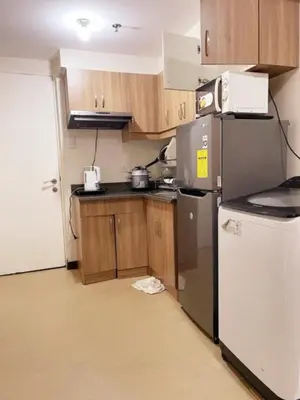 a kitchen with wooden cabinets and a refrigerator at Torre DeManila TaftAvenue KingBed1bedroomBalcony 65InchesTV Rooftop Viewing LunetaPark ManilaOcean ManilaBay US Embassy in Manila