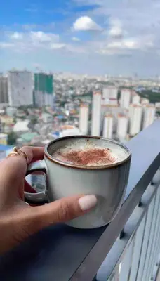 a person holding a cup of coffee on a balcony at Cozy 1BR with balcony at Fame Residences in Manila