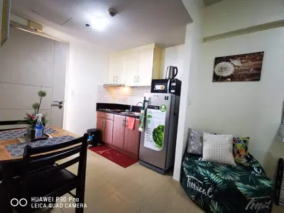 a kitchen with a refrigerator and a table with a chair at Pasay staycation @150Newport in Manila