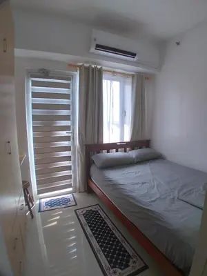 a bedroom with a large bed and a window at SM South Residences, 1 bedroom with balcony. in Manila