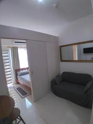 a small room with a couch and a bedroom at SM South Residences, 1 bedroom with balcony. in Manila