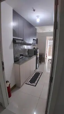 a kitchen with stainless steel appliances and a tile floor at SM South Residences, 1 bedroom with balcony. in Manila