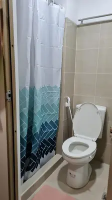 a bathroom with a toilet and a shower curtain at Chic Nordic Condo Unit at Shore Residences Mall of Asia in Manila
