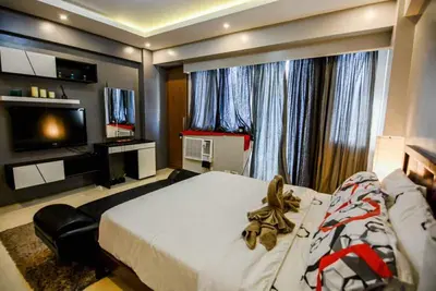 a bedroom with a large bed and a television at palm tree villas in Manila