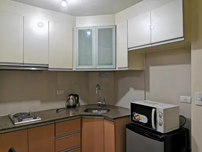 a kitchen with white cabinets and a sink and a microwave at palm tree villas in Manila