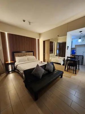 a bedroom with a large bed and a black couch at palm tree villas in Manila