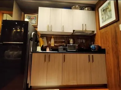 a kitchen with white cabinets and a black refrigerator at Stay Amare Green Residences Kristina in Manila