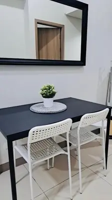 a black table with two white chairs and a potted plant at S Residences-MOA in Manila