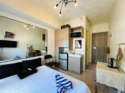 a bedroom with a white bed and a kitchen with a kitchen at Great View@Fully Equipped Condo w/ WiFi NETFLIX @the Metro in Manila