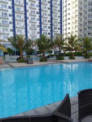 a large swimming pool with palm trees and buildings at SMDC Jazz Residences in Manila
