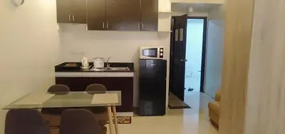 a small kitchen with a table and a refrigerator at KASELDORZHOSTEL TRANSIENT at Moonwalk Paranaque in Manila
