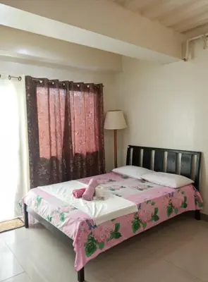 a bedroom with a bed with a pink blanket and a window at KASELDORZHOSTEL TRANSIENT at Moonwalk Paranaque in Manila