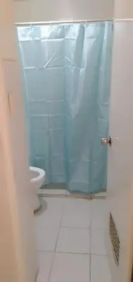 a bathroom with a toilet and a blue shower curtain at KASELDORZHOSTEL TRANSIENT at Moonwalk Paranaque in Manila