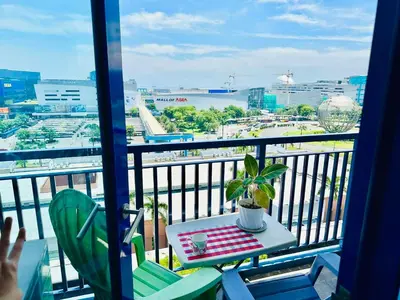 a balcony with a table and a view of a city at Sea Residences - Tino Val in Manila