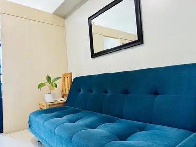 a blue couch in a room with a mirror at Sea Residences in Manila