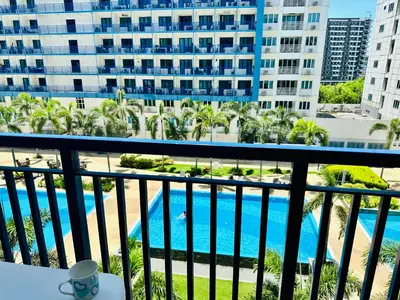 a balcony with a view of a pool and buildings at Sea Residences in Manila