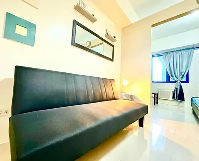 a black leather couch in a room with a window at Sea Residences in Manila