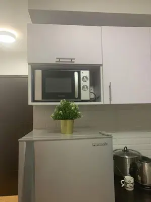 a microwave on top of a refrigerator in a kitchen at Minimalist 1 Bedroom in Alabang near Molito and ATC with WiFi & Netflix m in Manila
