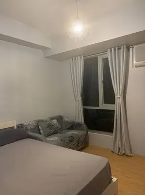 a bedroom with a bed and a couch and a window at Minimalist 1 Bedroom in Alabang near Molito and ATC with WiFi & Netflix m in Manila