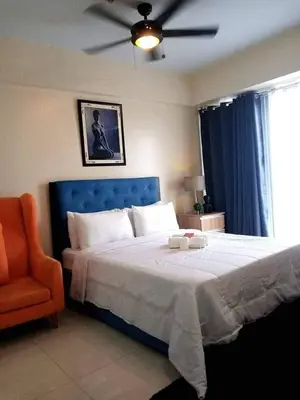 a bedroom with a bed with a blue headboard and a chair at Budget Apartment Manila across Manila Airport T3 in Manila