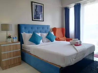 a bedroom with a large bed and an orange chair at Budget Apartment Manila across Manila Airport T3 in Manila