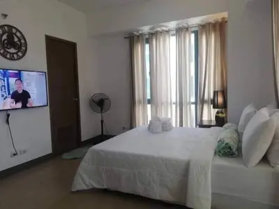 a bedroom with a white bed and a flat screen tv at Budget Apartment Manila across Manila Airport T3 in Manila