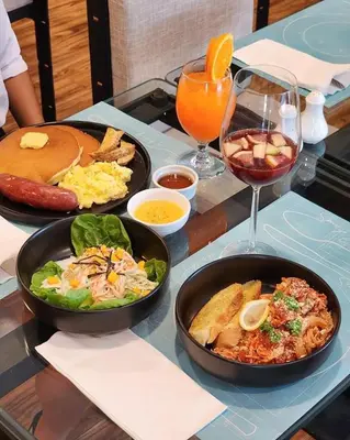 a table with two plates of food and a glass of wine at Fynn Boutique Hotel in Bacoor