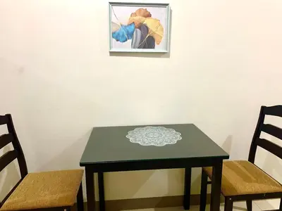a green table with two chairs and a picture on the wall at Sea Residences MOA by JO Alano New in Manila